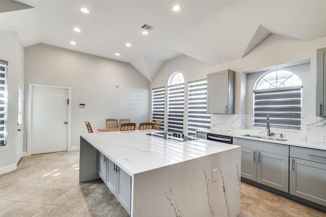 kitchen featuring gray cabinets, a kitchen island, lofted ceiling, and sink