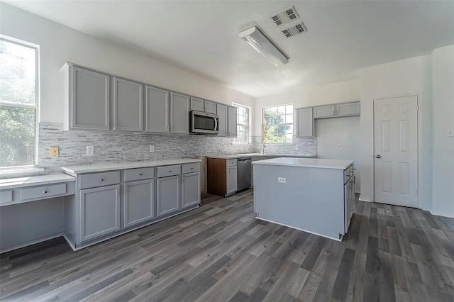 kitchen with appliances with stainless steel finishes, a center island, gray cabinets, and dark hardwood / wood-style flooring