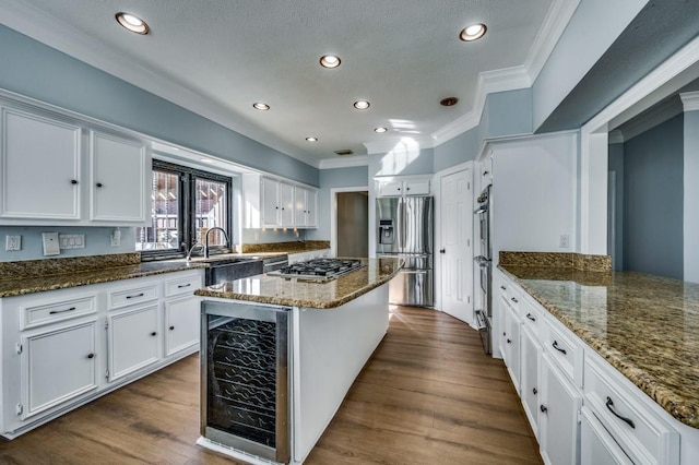 kitchen with dark stone counters, wine cooler, white cabinets, and stainless steel appliances