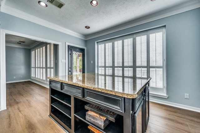 kitchen with light stone counters, plenty of natural light, hardwood / wood-style floors, and a textured ceiling