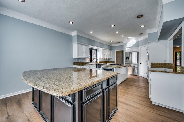 kitchen featuring a center island, light stone countertops, stainless steel fridge with ice dispenser, and white cabinetry