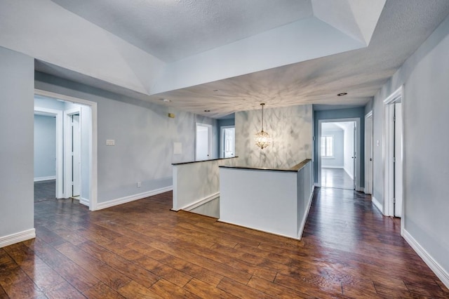 kitchen featuring dark hardwood / wood-style flooring, a raised ceiling, hanging light fixtures, and an inviting chandelier