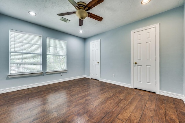 empty room with ceiling fan, dark hardwood / wood-style flooring, and a textured ceiling