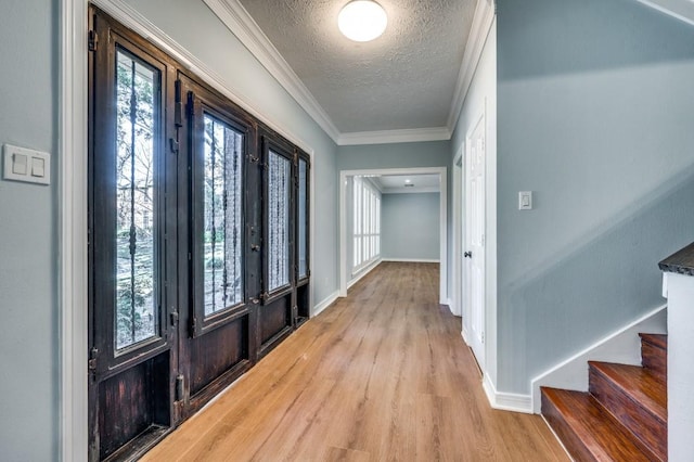 foyer entrance with french doors, light hardwood / wood-style floors, a textured ceiling, and ornamental molding