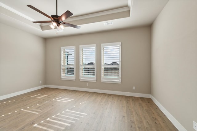 spare room featuring a tray ceiling, ceiling fan, hardwood / wood-style floors, and ornamental molding