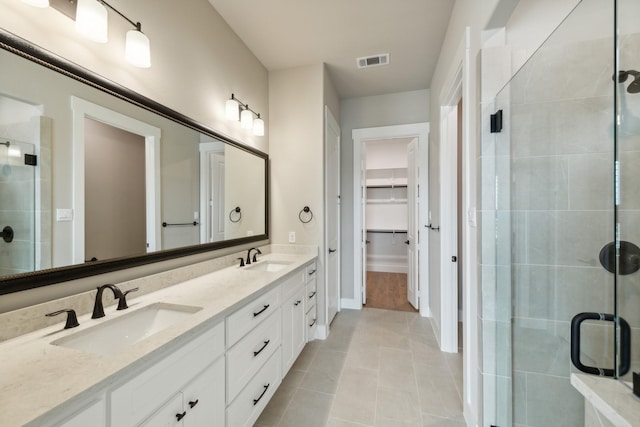 bathroom with tile patterned floors, vanity, and a shower with door