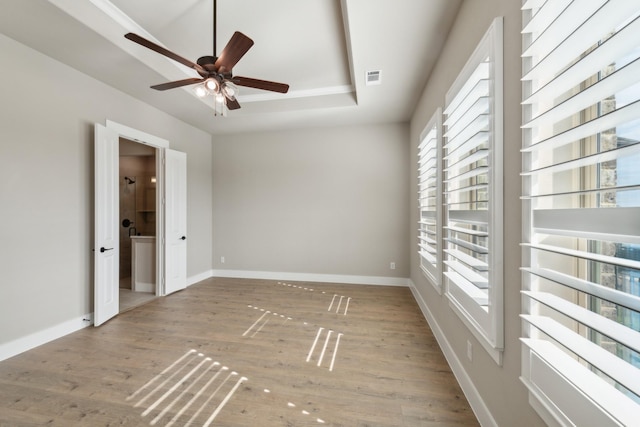 spare room featuring hardwood / wood-style floors, ceiling fan, and a raised ceiling