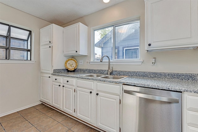 kitchen featuring dishwasher, sink, light tile patterned floors, a textured ceiling, and white cabinets