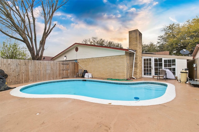 pool at dusk featuring a patio