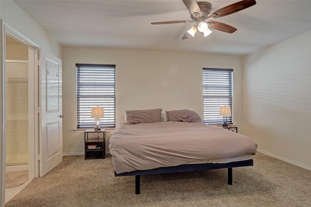 bedroom featuring light colored carpet, ceiling fan, and ensuite bath