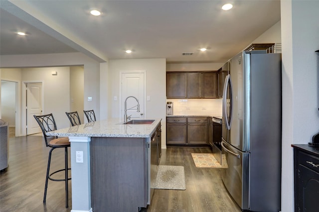 kitchen with dark wood-type flooring, a sink, visible vents, appliances with stainless steel finishes, and a center island with sink