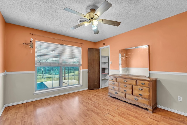 bedroom featuring ceiling fan, a closet, a textured ceiling, and light hardwood / wood-style floors