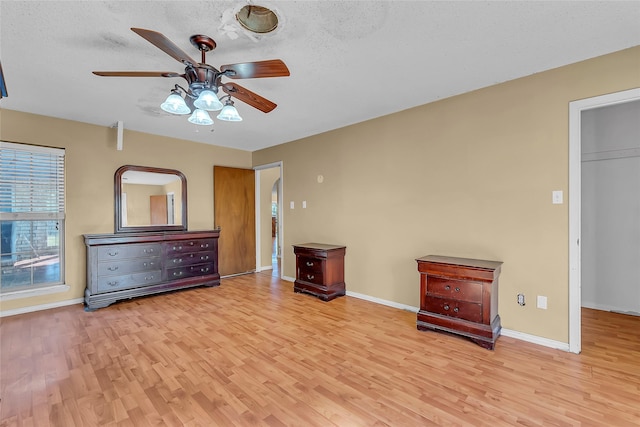 unfurnished bedroom with ceiling fan, light wood-type flooring, and a textured ceiling