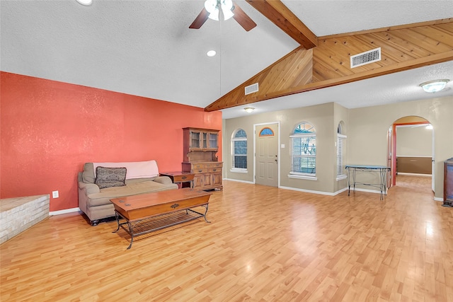 living room featuring ceiling fan, lofted ceiling with beams, a textured ceiling, and light hardwood / wood-style floors