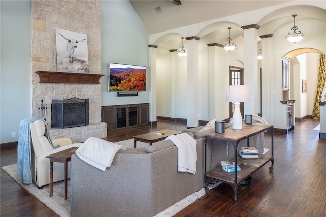 living room with high vaulted ceiling, dark wood-type flooring, and a stone fireplace