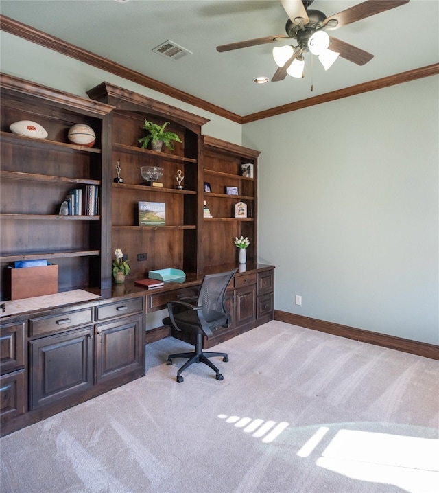 carpeted office featuring ceiling fan, crown molding, and built in desk