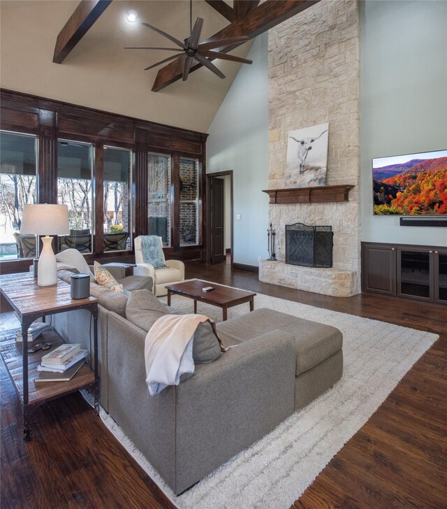 living room with ceiling fan, a fireplace, beamed ceiling, high vaulted ceiling, and dark hardwood / wood-style flooring