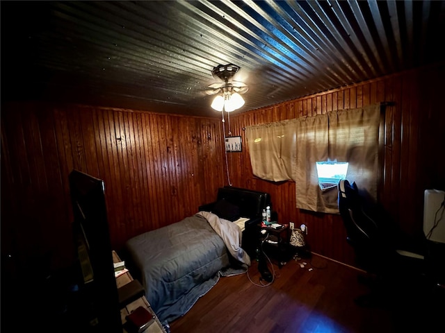 bedroom with ceiling fan and wood walls