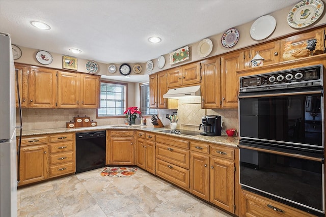 kitchen with sink, tasteful backsplash, light stone counters, and black appliances