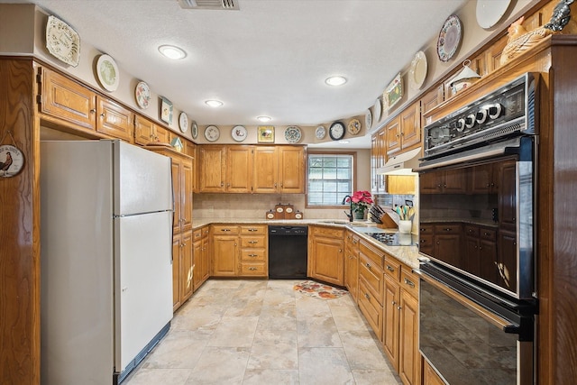 kitchen featuring black appliances, decorative backsplash, and sink