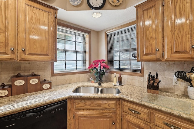 kitchen featuring light stone countertops, decorative backsplash, dishwasher, and sink