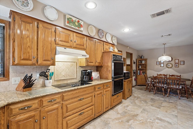 kitchen with black appliances, backsplash, light stone countertops, and decorative light fixtures