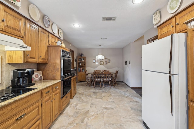 kitchen featuring tasteful backsplash, decorative light fixtures, double oven, light stone counters, and white refrigerator