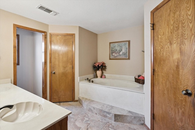 bathroom featuring a bath, a textured ceiling, and vanity