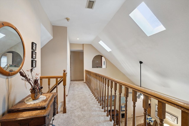 corridor with light colored carpet and vaulted ceiling with skylight