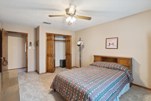 bedroom with ceiling fan, light colored carpet, a textured ceiling, and a closet