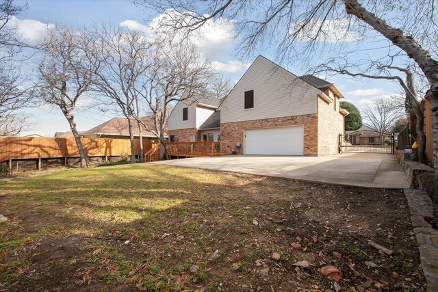 rear view of property with a yard, a wooden deck, and a garage