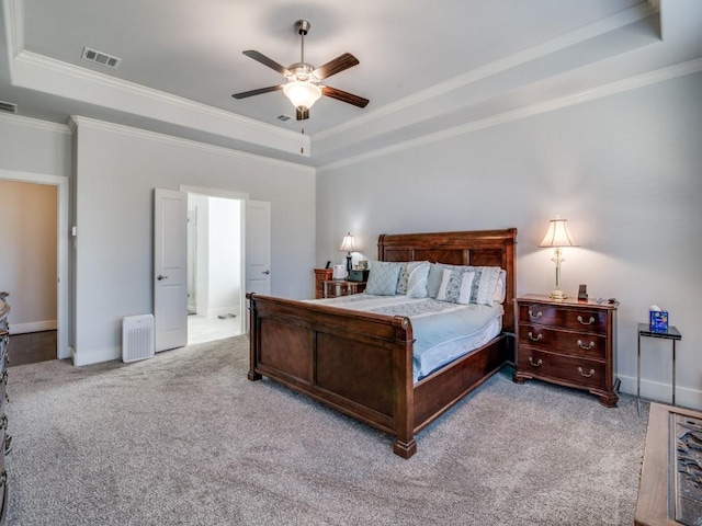 carpeted bedroom with a tray ceiling, ceiling fan, and crown molding