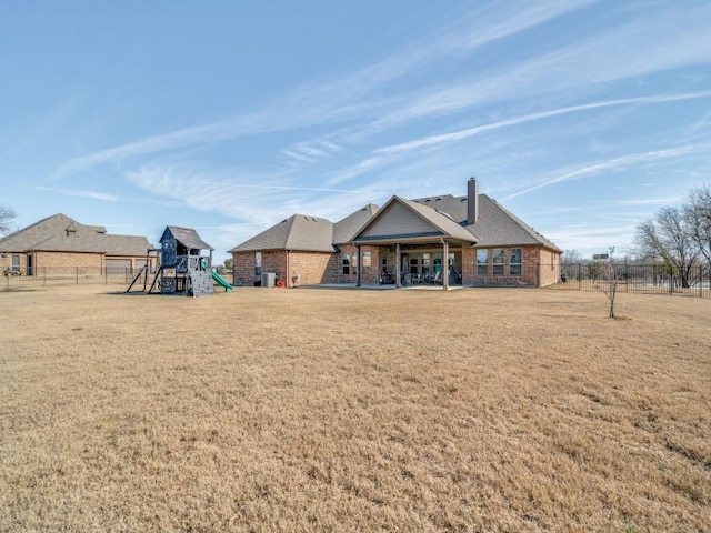 rear view of house with a playground and a yard