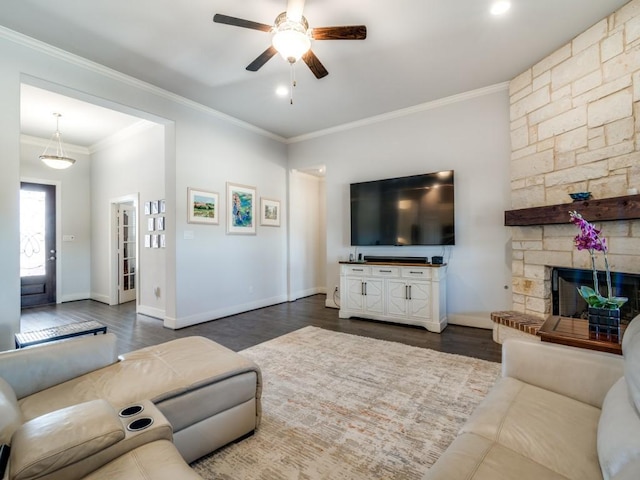 living room with a stone fireplace, crown molding, ceiling fan, and dark hardwood / wood-style floors