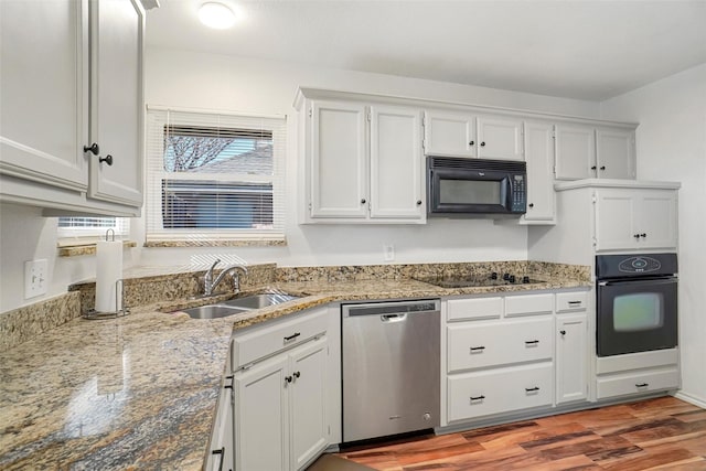 kitchen featuring hardwood / wood-style floors, black appliances, sink, light stone counters, and white cabinetry