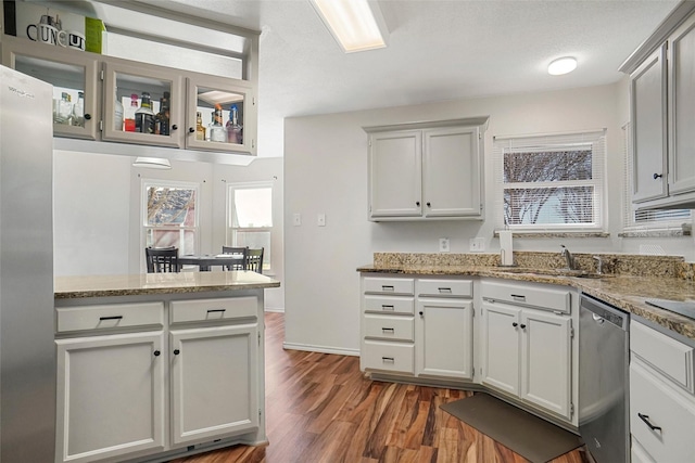 kitchen featuring stone counters, sink, stainless steel appliances, dark hardwood / wood-style flooring, and kitchen peninsula