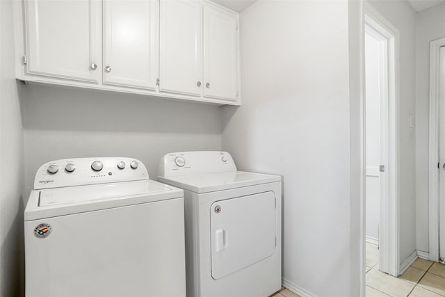 laundry room featuring cabinets, light tile patterned flooring, and washing machine and clothes dryer