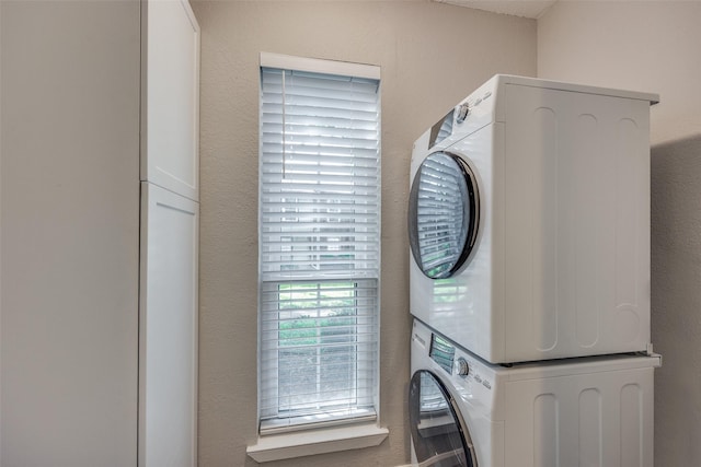 washroom with cabinets and stacked washer and clothes dryer