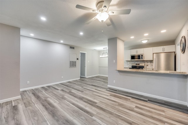 unfurnished living room featuring ceiling fan, sink, and light hardwood / wood-style floors