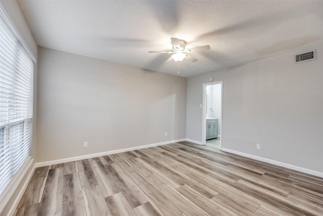 empty room featuring ceiling fan, light wood-type flooring, and a textured ceiling