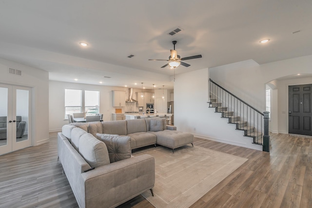 living room featuring french doors, light wood-type flooring, and ceiling fan