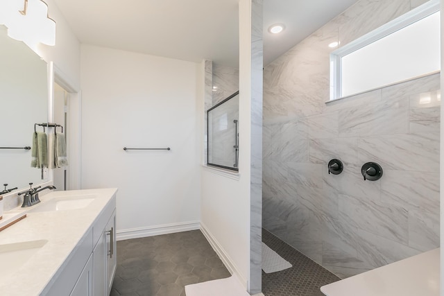 bathroom featuring tile patterned flooring, a tile shower, and vanity