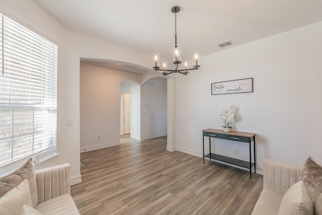 interior space with a healthy amount of sunlight, wood-type flooring, and a notable chandelier