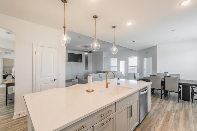 kitchen featuring dishwasher, a center island with sink, sink, hanging light fixtures, and ceiling fan