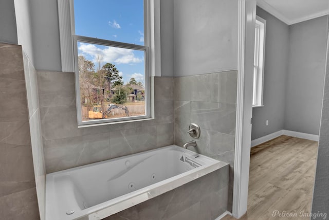 bathroom featuring hardwood / wood-style flooring, a relaxing tiled tub, and crown molding