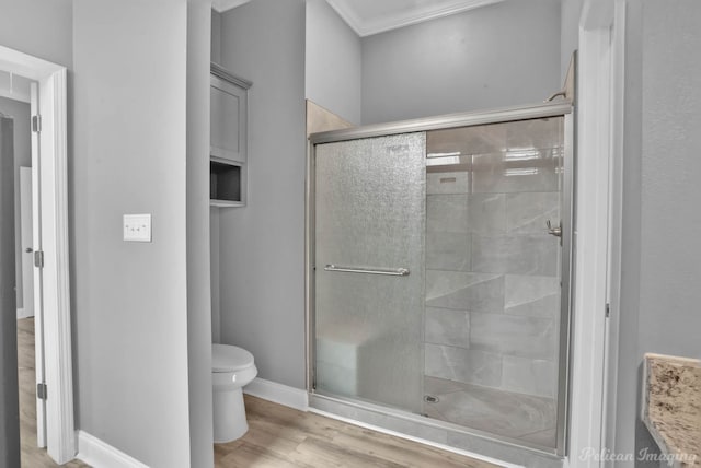 bathroom featuring crown molding, toilet, a shower with shower door, and wood-type flooring