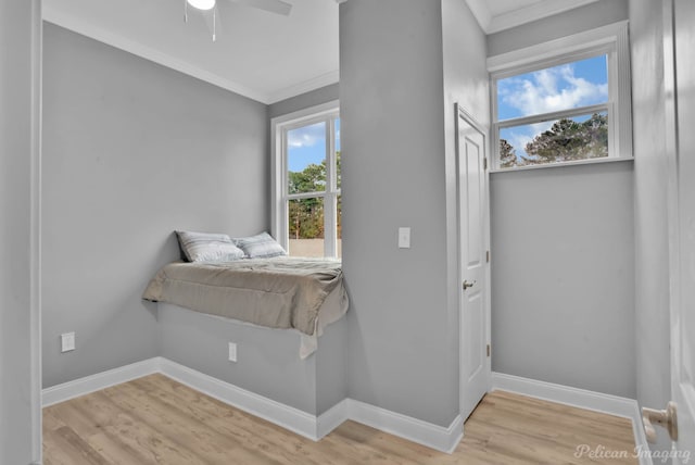 bedroom featuring ceiling fan, light wood-type flooring, ornamental molding, and multiple windows