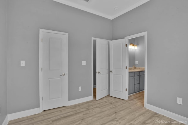 unfurnished bedroom featuring light wood-type flooring, ensuite bath, crown molding, and sink