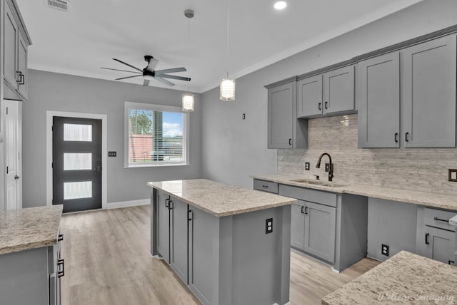 kitchen featuring gray cabinets, a kitchen island, ceiling fan, and sink