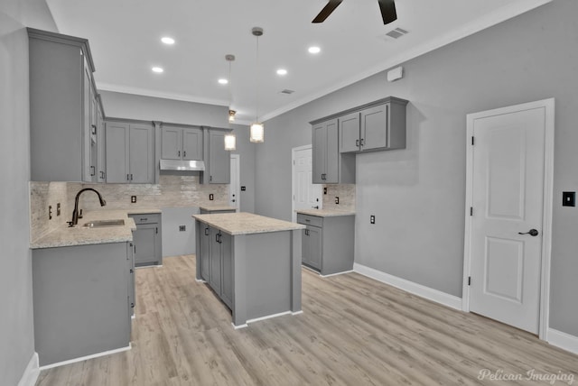 kitchen featuring gray cabinetry, a center island, hanging light fixtures, and sink